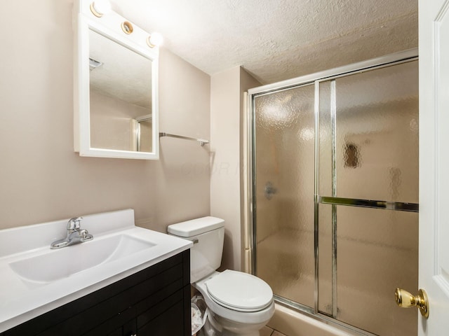 full bathroom featuring vanity, a shower stall, toilet, and a textured ceiling