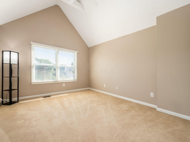 spare room with light carpet, visible vents, high vaulted ceiling, and baseboards