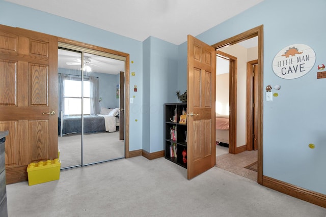 bedroom with a closet, light carpet, and baseboards