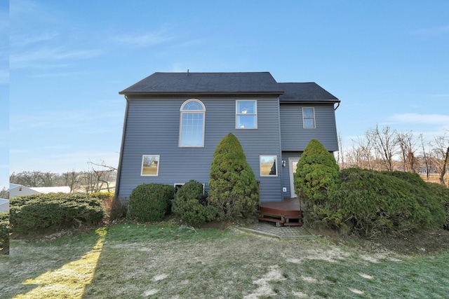 back of property with a yard, a shingled roof, and a deck