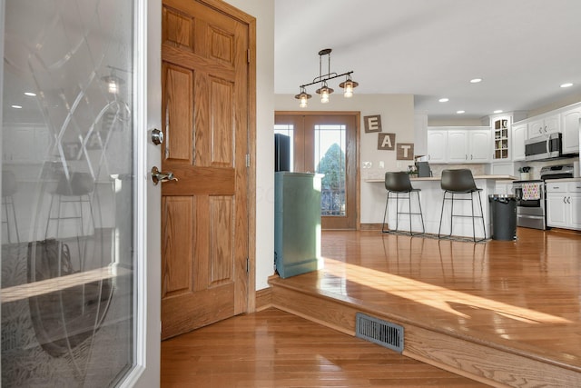 foyer featuring recessed lighting, wood finished floors, visible vents, and baseboards