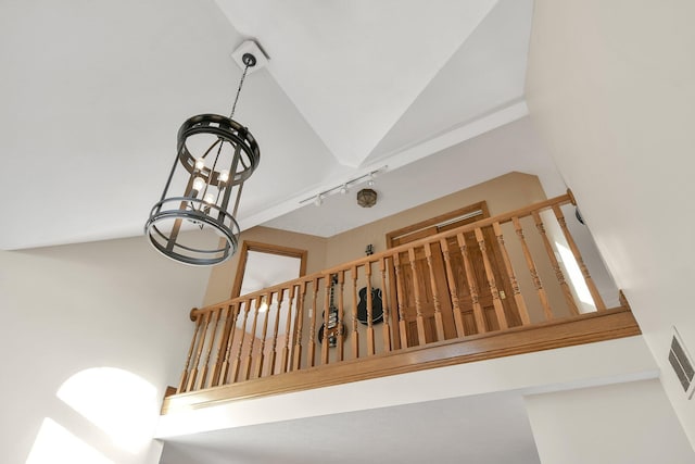 staircase featuring an inviting chandelier, visible vents, and lofted ceiling