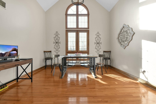 interior space with light wood finished floors, high vaulted ceiling, and baseboards