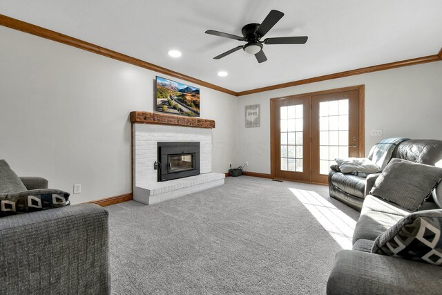 carpeted living room featuring a fireplace, crown molding, a ceiling fan, and baseboards