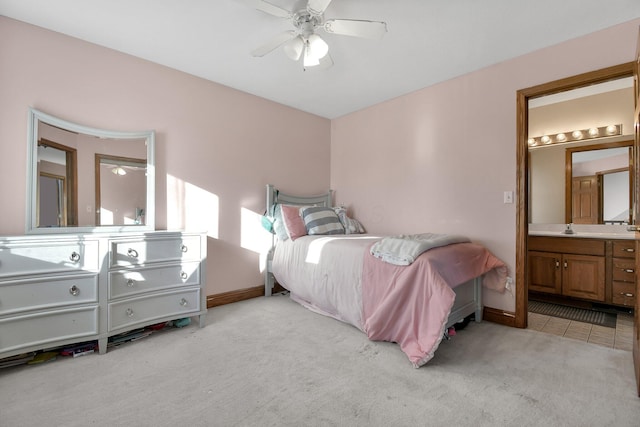 bedroom with a sink, light carpet, ensuite bath, and a ceiling fan