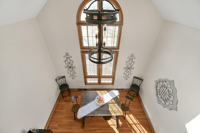 foyer entrance featuring a wealth of natural light, a notable chandelier, a towering ceiling, and wood finished floors