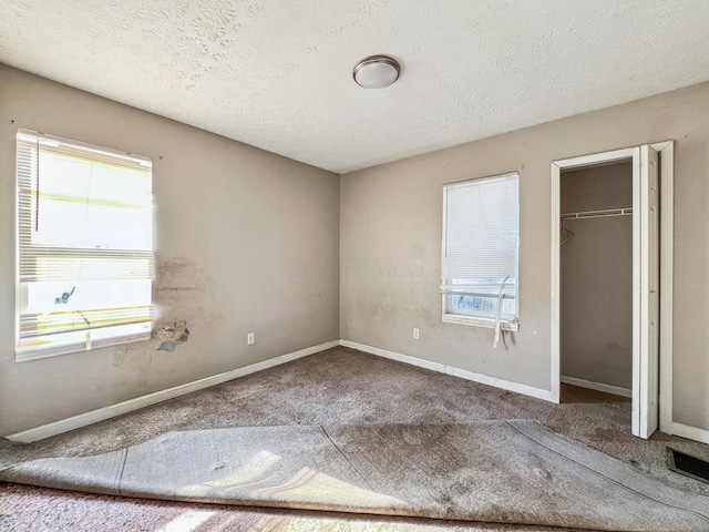 unfurnished bedroom with visible vents, carpet, baseboards, a closet, and a textured ceiling