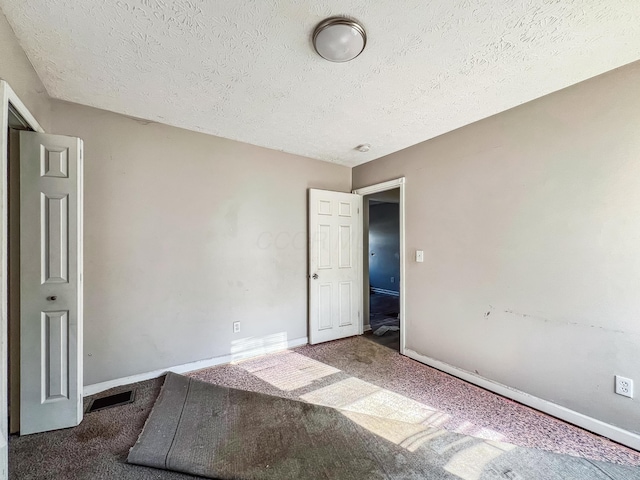 unfurnished bedroom with carpet flooring, a textured ceiling, baseboards, and visible vents