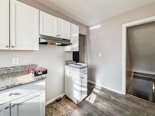 kitchen featuring white cabinetry, baseboards, under cabinet range hood, wood finished floors, and a textured ceiling