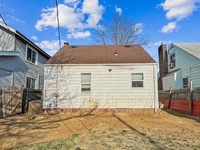 rear view of house featuring crawl space, roof with shingles, and fence