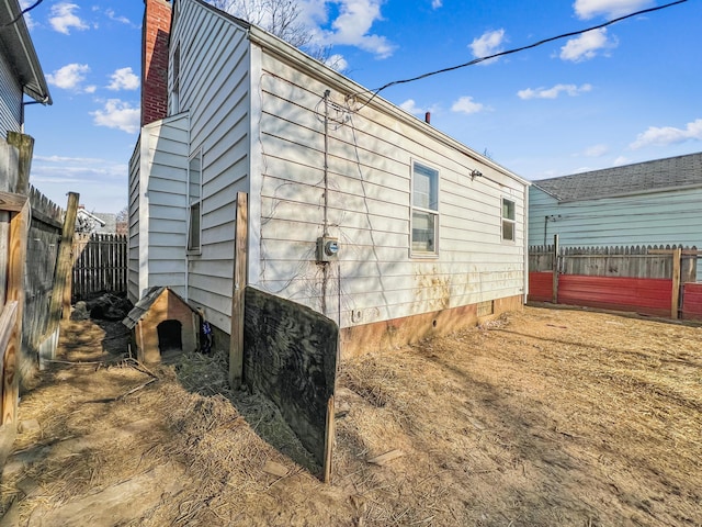 view of side of home with a chimney and fence