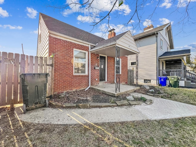 view of front of home featuring brick siding and fence