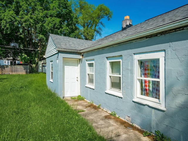 view of home's exterior featuring a lawn, a chimney, and fence