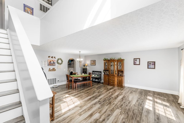 dining area with wood finished floors, visible vents, stairs, a textured ceiling, and a chandelier