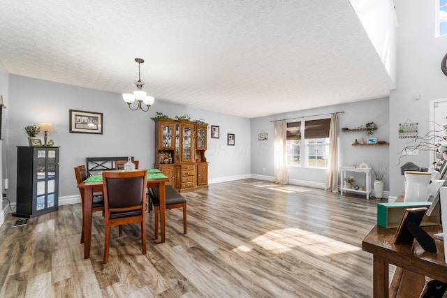 dining room with a chandelier, baseboards, a textured ceiling, and wood finished floors