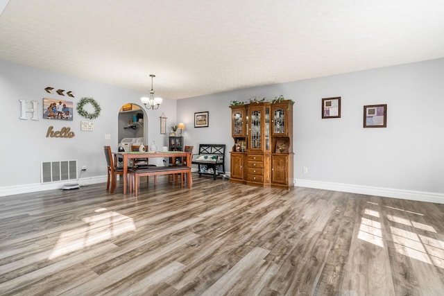 unfurnished dining area featuring visible vents, baseboards, wood finished floors, and a chandelier