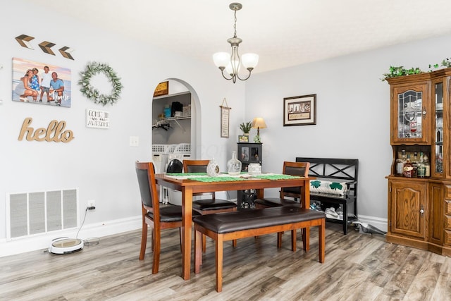 dining space with baseboards, visible vents, light wood finished floors, and a chandelier