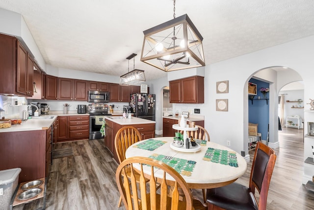 dining area with arched walkways, dark wood finished floors, and a textured ceiling