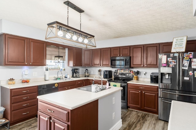 kitchen with a sink, appliances with stainless steel finishes, dark wood-style floors, and light countertops