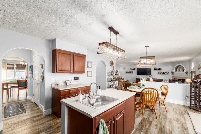 kitchen with a sink, light wood-style flooring, arched walkways, and open floor plan