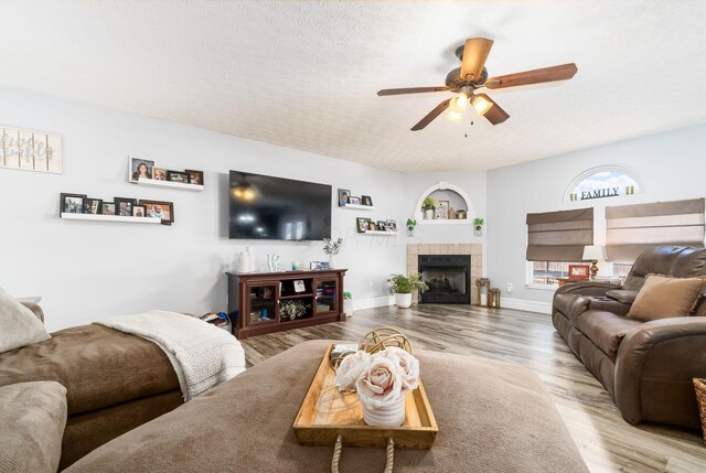 living area with wood finished floors, a ceiling fan, baseboards, and a textured ceiling