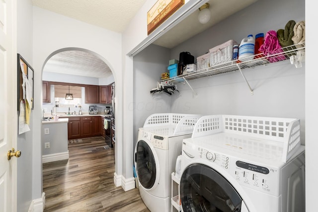 washroom with laundry area, washing machine and dryer, arched walkways, and a textured ceiling