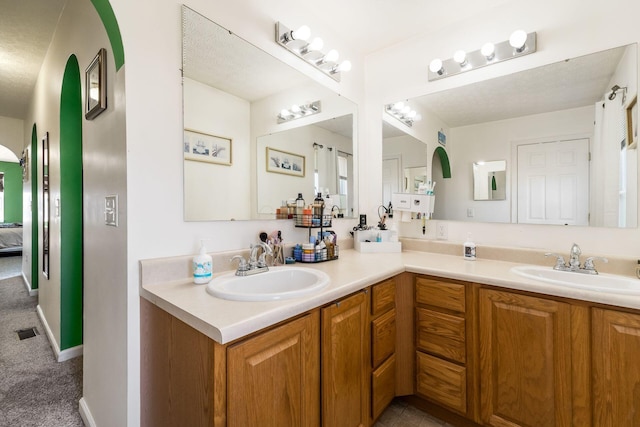 ensuite bathroom with ensuite bath, double vanity, visible vents, and a sink