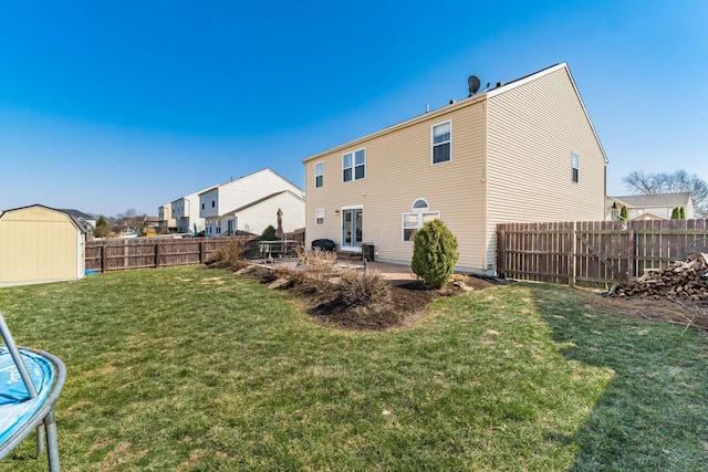 rear view of house with an outdoor structure, a storage unit, a lawn, and a fenced backyard