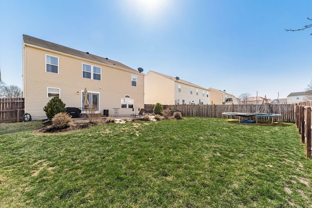 back of property featuring a patio, a trampoline, a lawn, and a fenced backyard