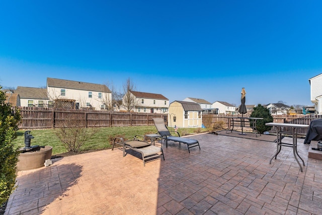 view of patio featuring a fenced backyard, a residential view, a storage shed, and an outdoor structure