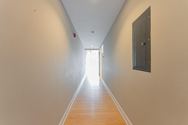 hallway with light wood-style flooring, electric panel, and baseboards