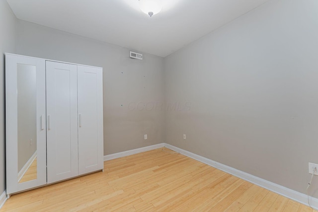 unfurnished bedroom with visible vents, light wood-type flooring, a closet, and baseboards