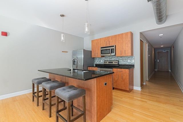 kitchen with decorative backsplash, brown cabinets, stainless steel appliances, and a sink