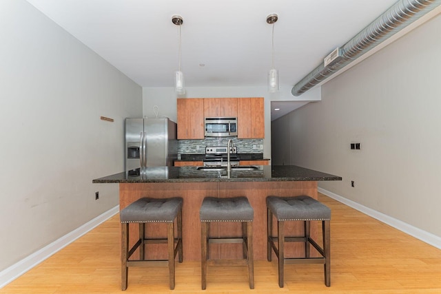 kitchen with backsplash, appliances with stainless steel finishes, a breakfast bar, and a sink