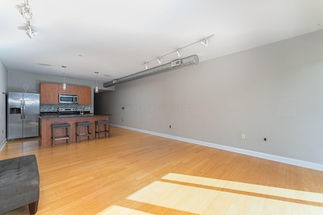 kitchen featuring dark countertops, open floor plan, a breakfast bar, light wood-style floors, and stainless steel appliances