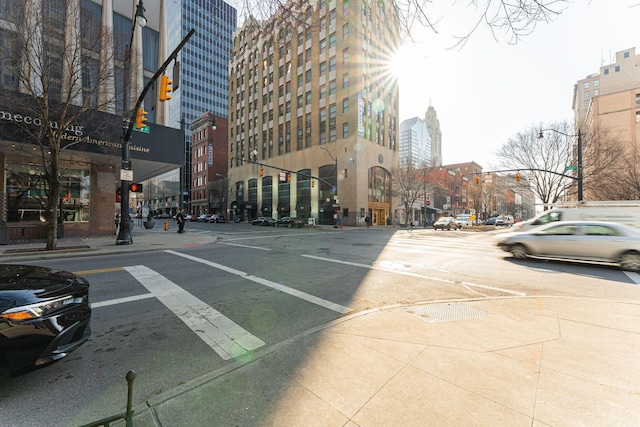 view of street with traffic lights, street lighting, a city view, curbs, and sidewalks