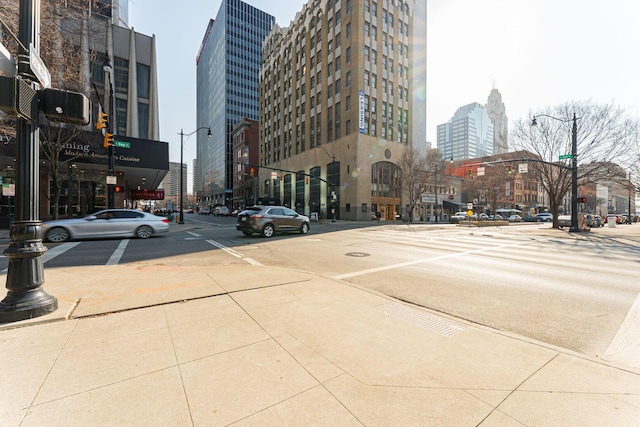 view of road featuring curbs, a view of city, traffic lights, street lights, and sidewalks