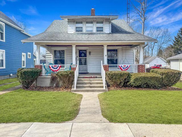 bungalow-style house with a chimney, roof with shingles, a porch, and a front lawn