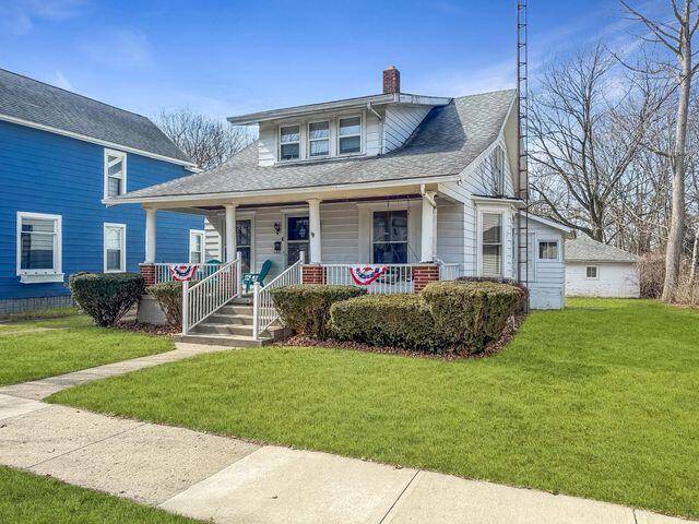 view of front of home featuring a front lawn, covered porch, and a chimney