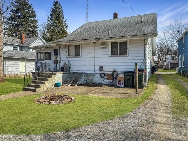 812 S Main St, Urbana, OH 43078 - rear view of property featuring a yard, roof with shingles, and a chimney