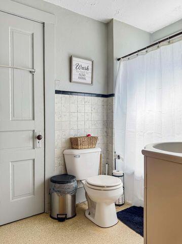 812 S Main St, Urbana, OH 43078 - bathroom featuring a wainscoted wall, toilet, a textured ceiling, tile walls, and vanity