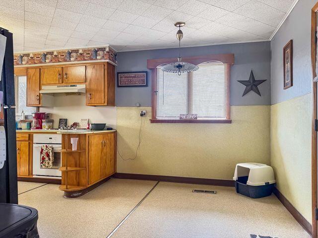 812 S Main St, Urbana, OH 43078 - kitchen with brown cabinetry, visible vents, oven, light countertops, and under cabinet range hood