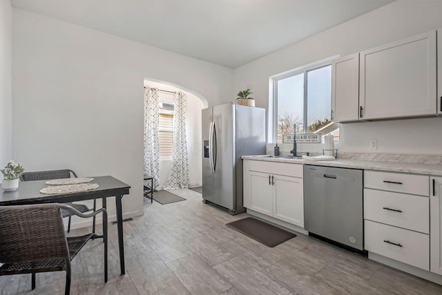 kitchen with a healthy amount of sunlight, white cabinets, stainless steel appliances, and light countertops