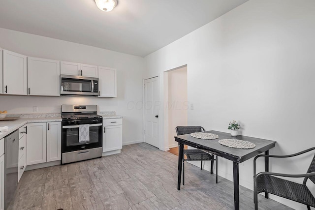 kitchen featuring white cabinets, light wood-style floors, baseboards, and appliances with stainless steel finishes