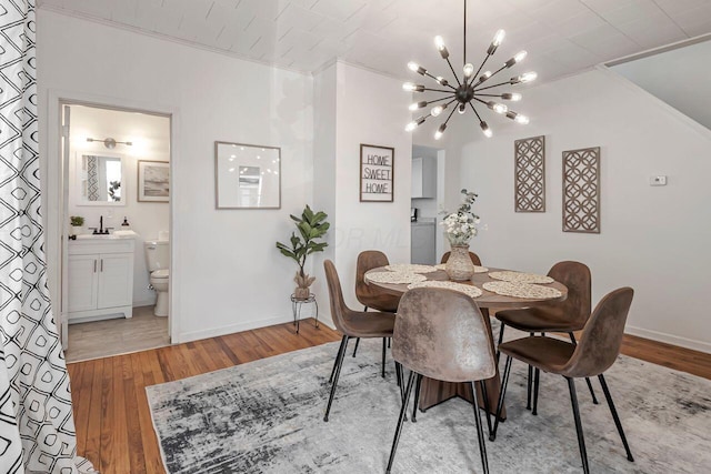 dining room featuring baseboards, an inviting chandelier, light wood-style flooring, and crown molding