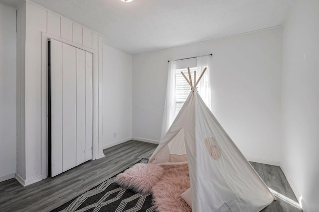 unfurnished bedroom featuring a textured ceiling, baseboards, and wood finished floors