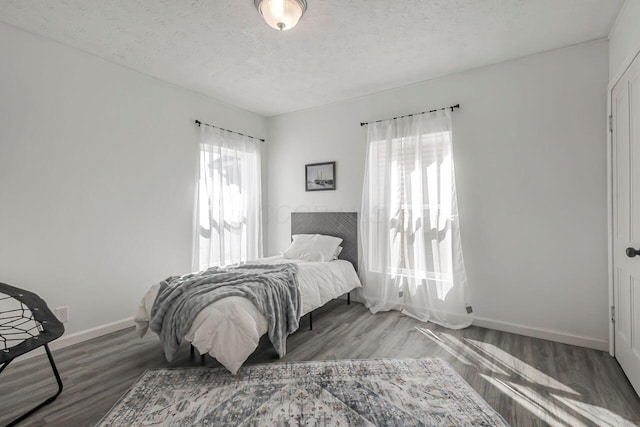 bedroom featuring a textured ceiling, baseboards, and wood finished floors