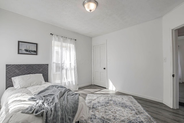 bedroom with baseboards, a textured ceiling, and wood finished floors