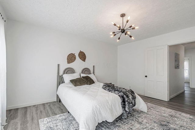 bedroom featuring a notable chandelier, wood finished floors, and a textured ceiling