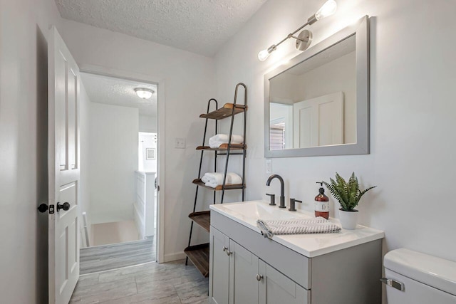 bathroom with toilet, a textured ceiling, and vanity